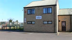 Norwood Building photo A small, tan brick building with a sign reading "Village Hall" and an empty car park in front.